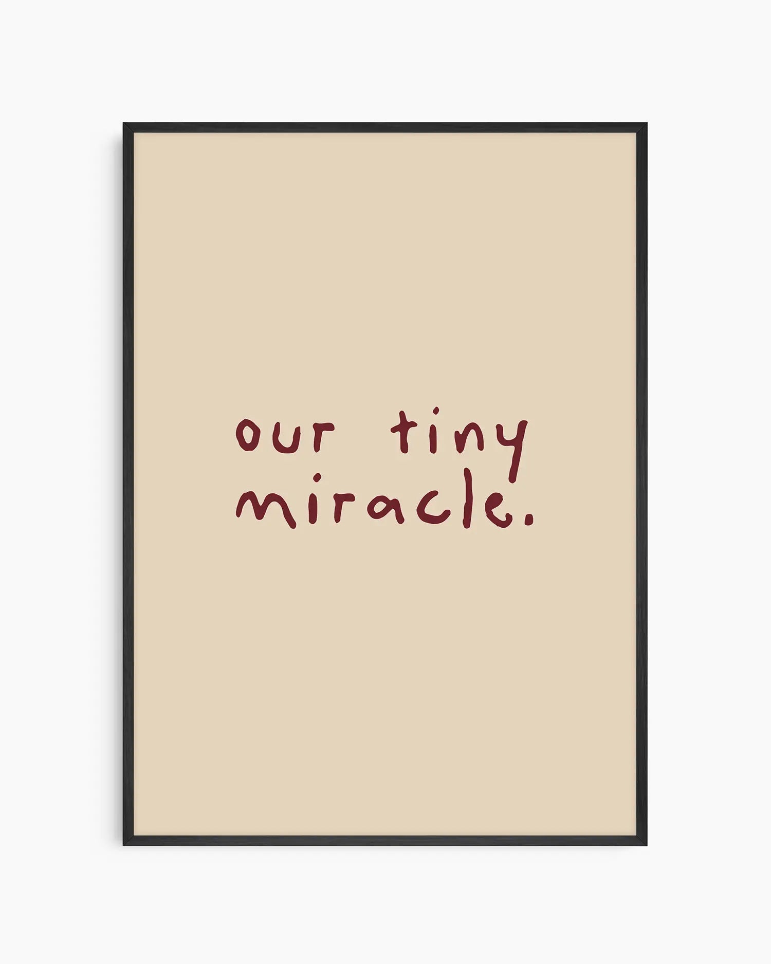Beige nursery poster with 'our tiny miracle.' text in brown framed in a black frame.