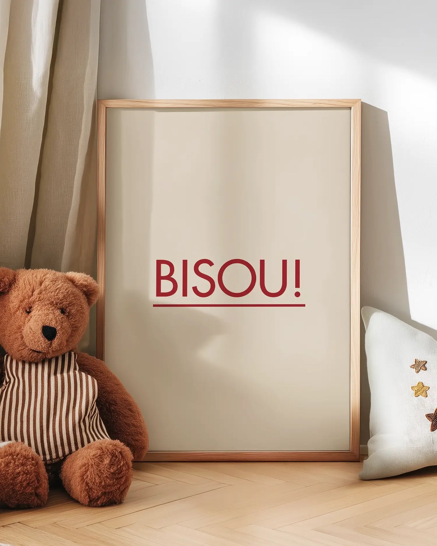 Poster with 'BISOU!' text next to a teddy bear on a wooden floor.