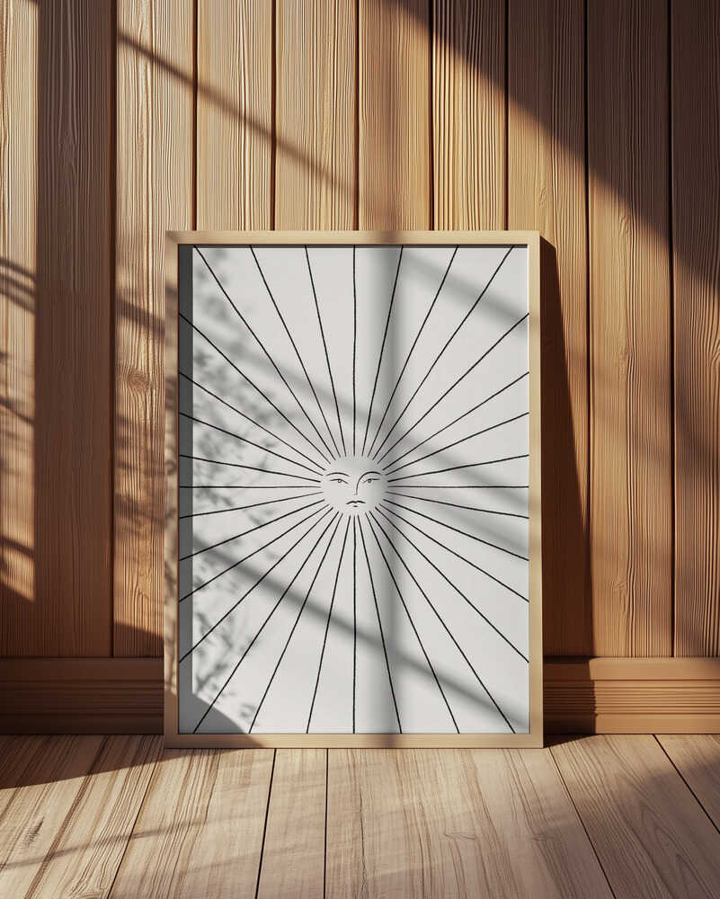Minimalist sun illustration art print in black and white, featuring a stylized sun with rays spreading outward from the center. Displayed in a light wooden frame leaning against a wooden wall, with natural sunlight and soft shadows. Perfect modern wall art for Scandinavian interiors.
