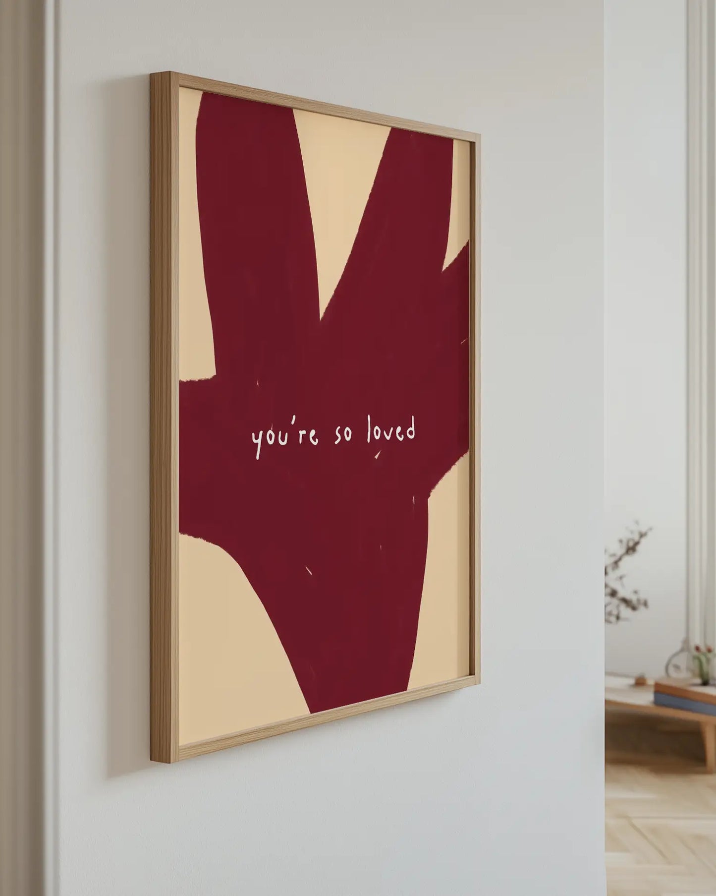 Framed abstract art with 'you're so loved' text on a white wall.