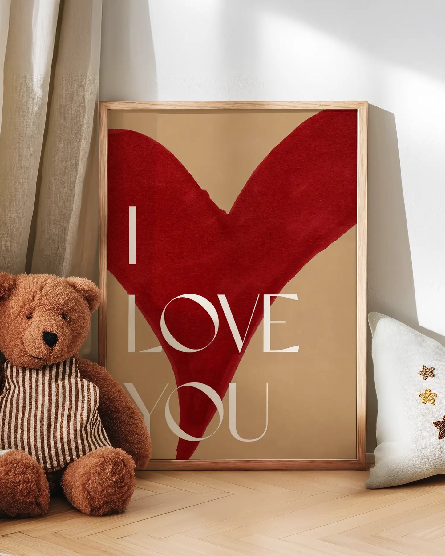 Artwork with a red heart and 'I LOVE YOU' text next to a teddy bear on a wooden floor.