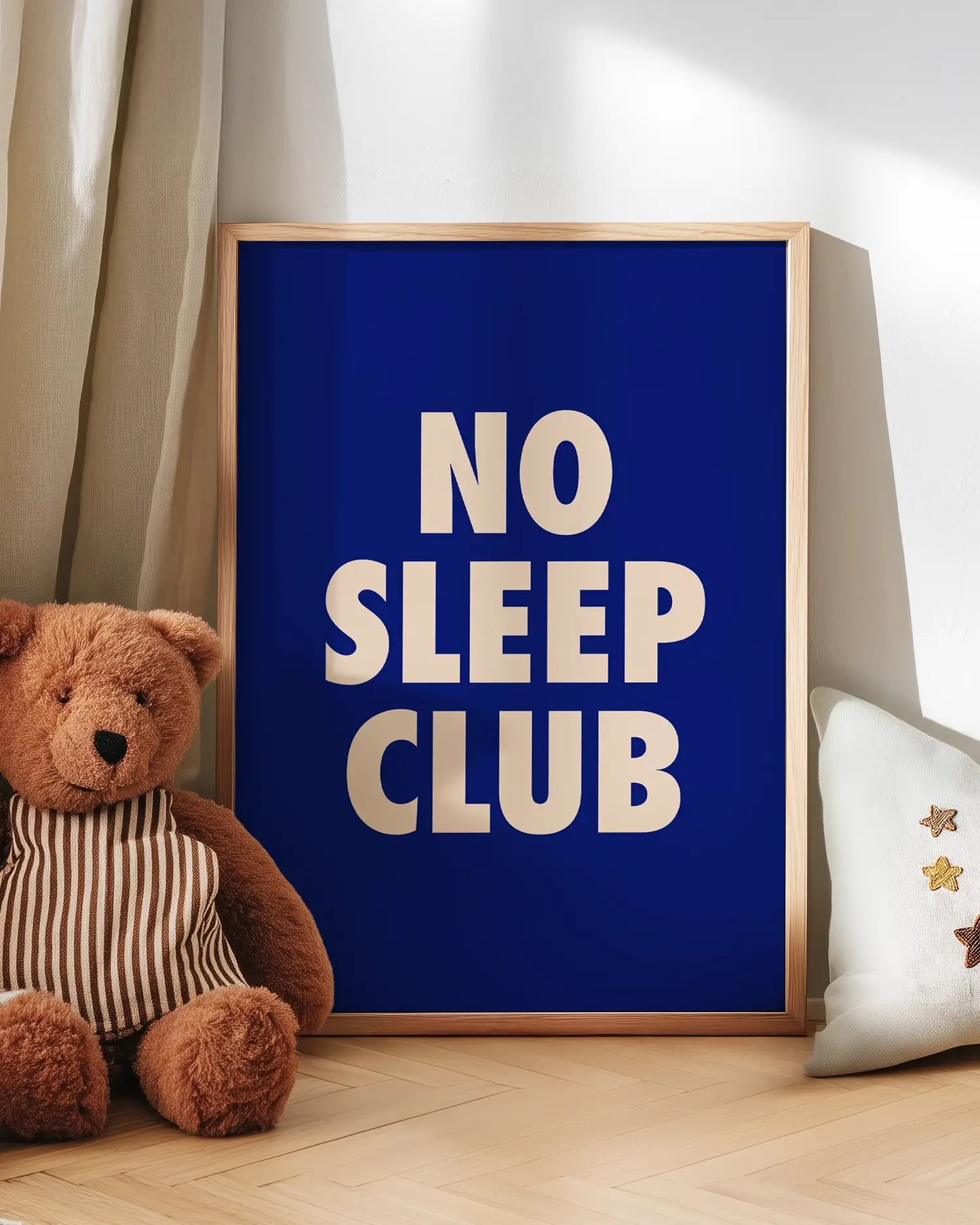 Poster with 'NO SLEEP CLUB' text next to a teddy bear on a wooden floor.
