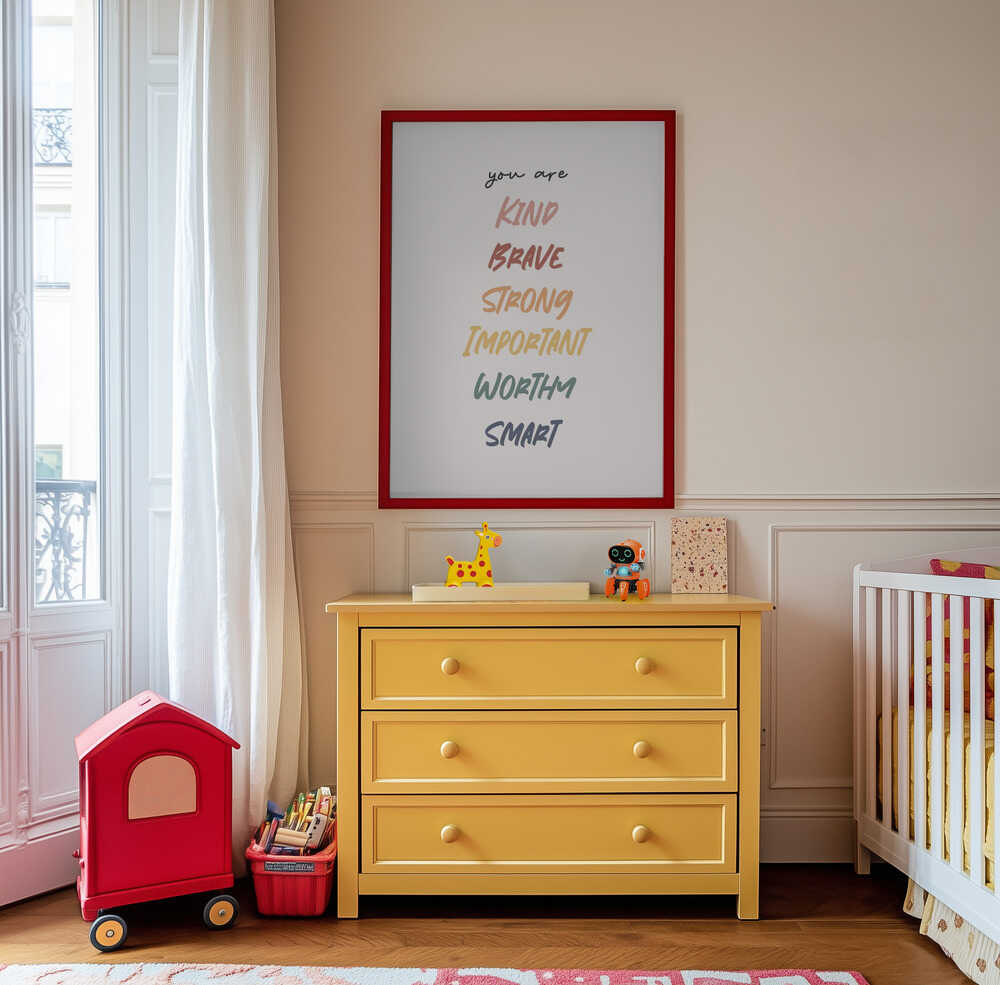 Framed positive affirmation poster hanging above a yellow dresser in a playful kids room. Uplifting text “You are kind, brave, strong, important, worthy, smart.” Ideal for nursery decor, emotional support wall art, and confidence-building children’s spaces.