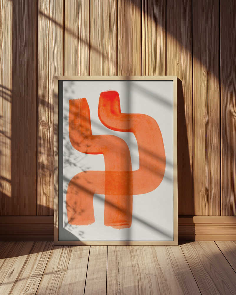 Framed terracotta abstract art print with bold orange brushstrokes on a light background, softly lit by sunlight in a wooden interior.