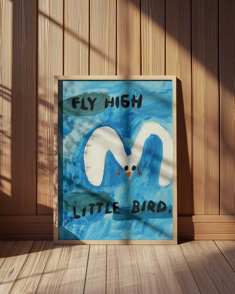 Framed “Fly High Little Bird” poster featuring a white bird soaring across a blue watercolor sky with black handwritten text, displayed in a cozy wood-paneled room.
